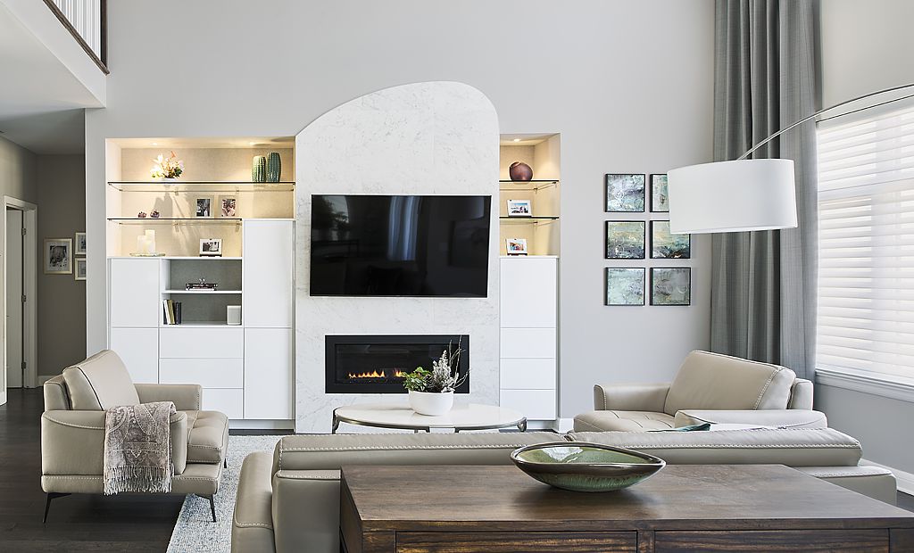 The TV contrasts against the marble fireplace but is softened by the lighting, cabinetry and the unusual shape of the fireplace surround.