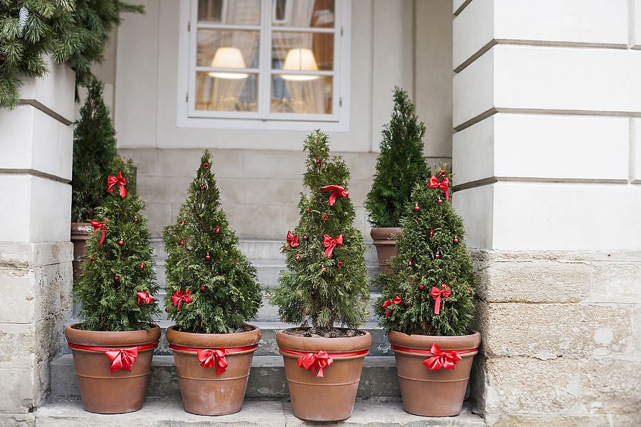 Decorated with red bows and balls Christmas trees in pots near house